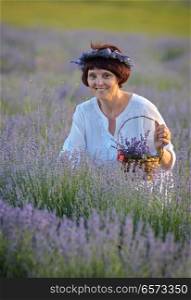 Beautiful woman holding lavender in a sunset field. Beautiful woman holding lavender in basket