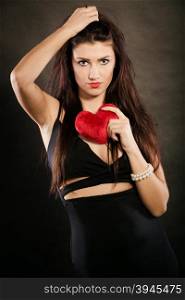 Beautiful woman holds red heart on black. Woman brunette long hair girl wearing black sensual dress holding gift in form of red heart love symbol studio shot on dark. Valentines day happiness concept
