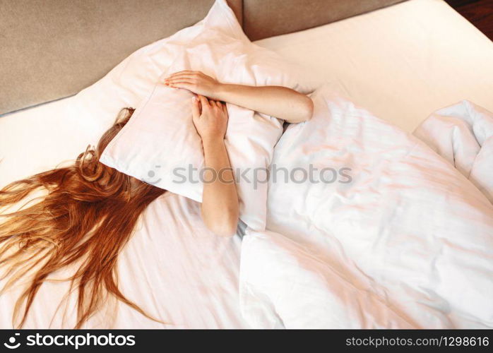 Beautiful woman hugs pillow, waking up. Morning bedding at home, relaxation in bedroom. Beautiful woman hugs pillow, waking up