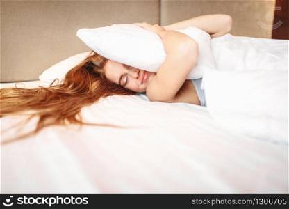 Beautiful woman hugs pillow, waking up. Morning bedding at home, relaxation in bedroom