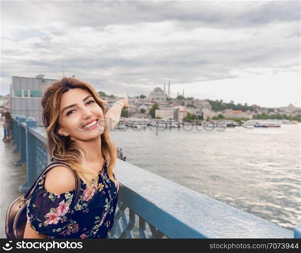 Beautiful woman in a dress shows mosque on Galata Bridge in Istanbul,Turkey. Beautiful woman in a dress shows mosque on Galata Bridge