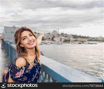 Beautiful woman in a dress shows mosque on Galata Bridge in Istanbul,Turkey. Beautiful woman in a dress shows mosque on Galata Bridge