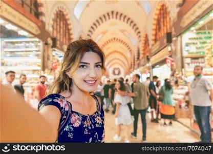 Beautiful woman in a dress takes selfie in Egypt Bazaar in Eminonu,Istanbul,Turkey. Beautiful woman in a dress takes selfie in Egypt Bazaar