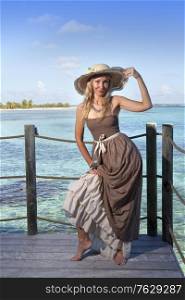 beautiful woman in a long dress on a wooden platform over the sea