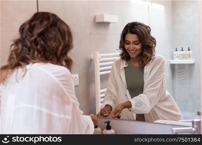 Beautiful woman in a modern bathroom moisturizing her skin
