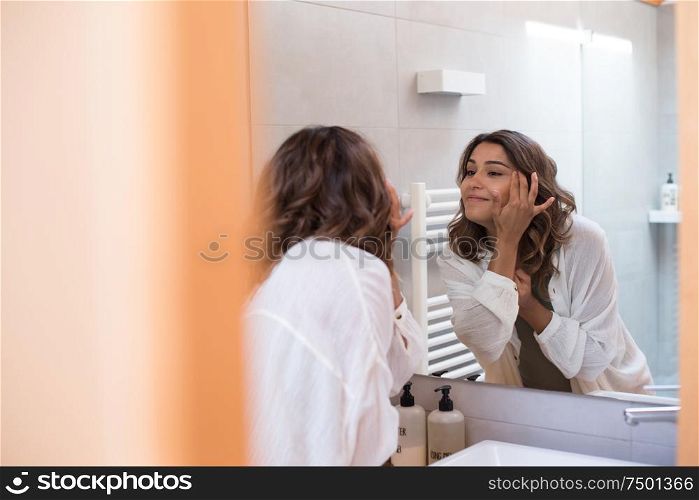 Beautiful woman in a modern bathroom moisturizing her skin