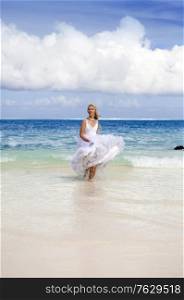 beautiful woman in a wedding dress on sand at sea edge