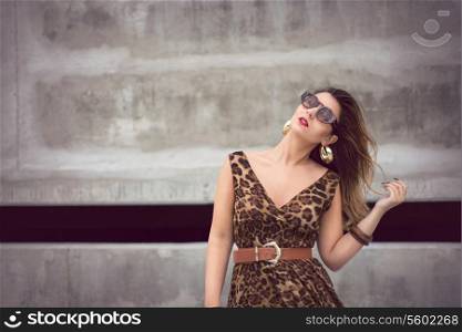 Beautiful woman in animal print dress in urban concrete jungle background