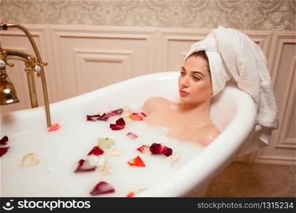 Beautiful woman in bathroom with rose petals.