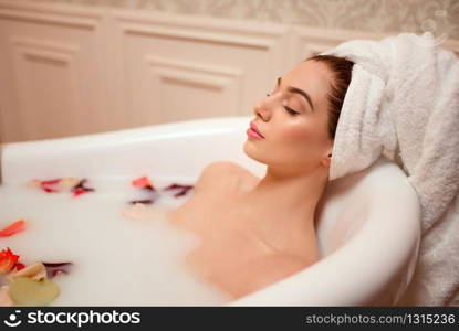 Beautiful woman in bathroom with rose petals and foam.