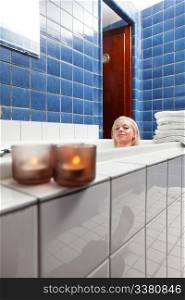 Beautiful woman in bathtub at luxury spa with candle in the glass