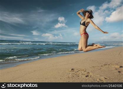 Beautiful woman in bikini jumping at the beach