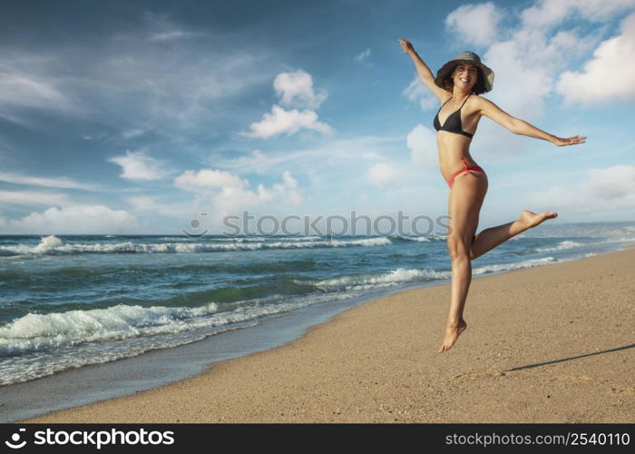 Beautiful woman in bikini jumping at the beach