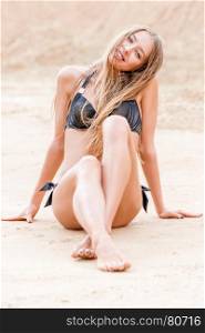 beautiful woman in bikini sitting on the sand near the sea