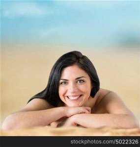 Beautiful woman in bikini sunbathing at the seaside looking at camera and smiling