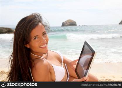 Beautiful woman in bikini using tablet on the beach