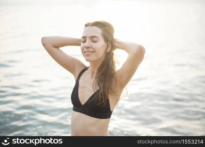 Beautiful woman in black bikini is enjoying with sea water on the beach