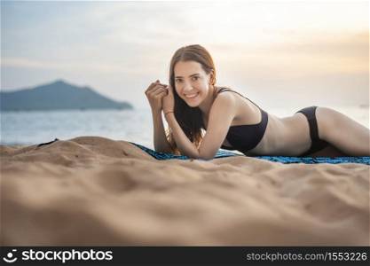 Beautiful woman in black bikini is lay down on the beach