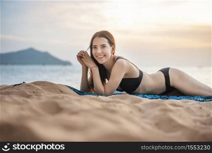 Beautiful woman in black bikini is lay down on the beach