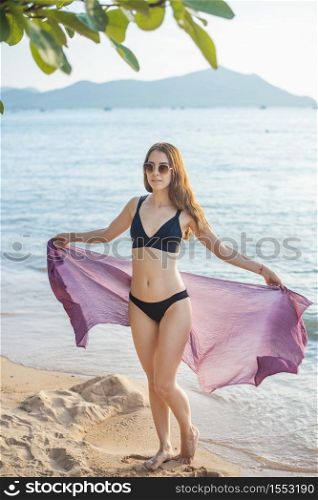 Beautiful woman in black bikini is relaxing on the beach, summer concept
