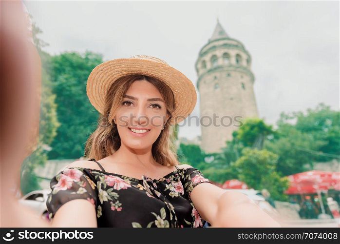Beautiful woman in black dress takes selfie in front of landmark Galata tower in Beyoglu,Istanbul,Turkey. Beautiful woman in black dress takes selfie in front of landmark Galata tower