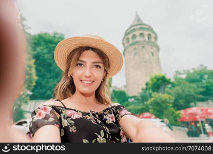 Beautiful woman in black dress takes selfie in front of landmark Galata tower in Beyoglu,Istanbul,Turkey. Beautiful woman in black dress takes selfie in front of landmark Galata tower