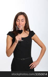 Beautiful woman in black dress tasting red wine