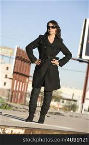 Beautiful woman in black trenchcoat and sunglasses at train yard