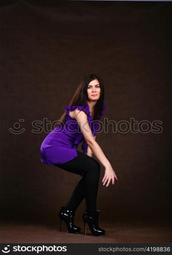 Beautiful woman in blue shirt and black leggings. Posing on brown background.