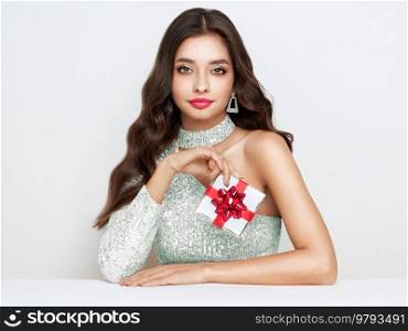 Beautiful woman in cocktail dress with gift box in hands. Beauty model with long curly hair. Christmas or New Year festivities. Holiday and Party