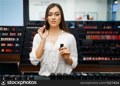 Beautiful woman in cosmetics store, front view. Buyer at the showcase in luxury beauty shop salon, female customer in fashion market. Beautiful woman in cosmetics store, front view