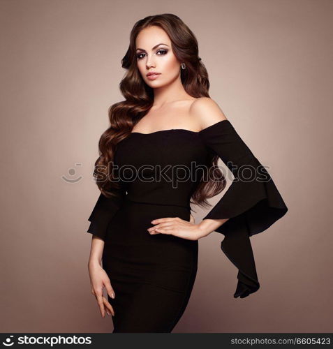 Beautiful woman in elegant black evening dress. Brunette Girl with Long Healthy and Shiny Curly Hair. Care and Beauty. Beautiful Model Woman with Wavy Hairstyle