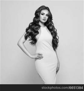Beautiful Woman in Elegant white Evening Dress. Brunette Girl with Long Healthy and Shiny Curly Hair. Care and Beauty. Beautiful Model Woman with Wavy Hairstyle