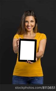 Beautiful woman in front of a black wall showing something on a tablet