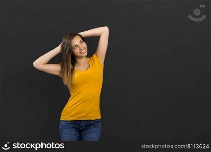 Beautiful woman in front of a black wall with a thoughtful expression