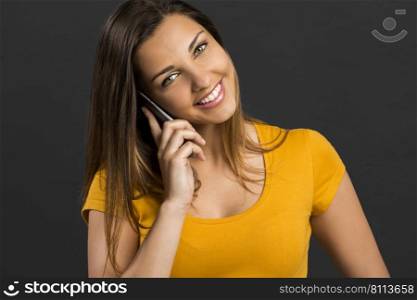 Beautiful woman in front of a dark wall talking at phone