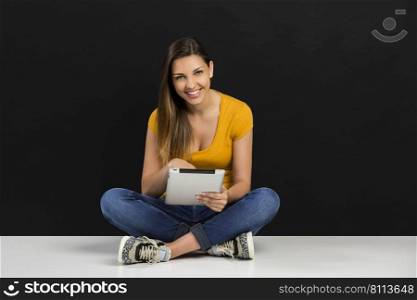 Beautiful woman in front of  ablack wall working with a tablet