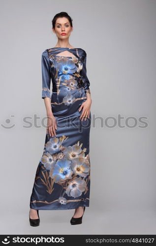 Beautiful woman in full length posing in a long blue dress with flowers, isolated.