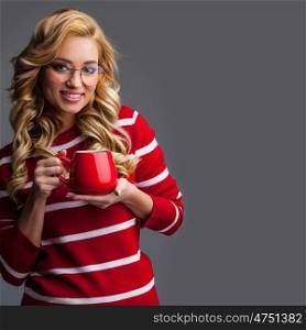 Beautiful woman in glasses holding red cup, studio shot