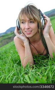 Beautiful woman in green field with headphones on