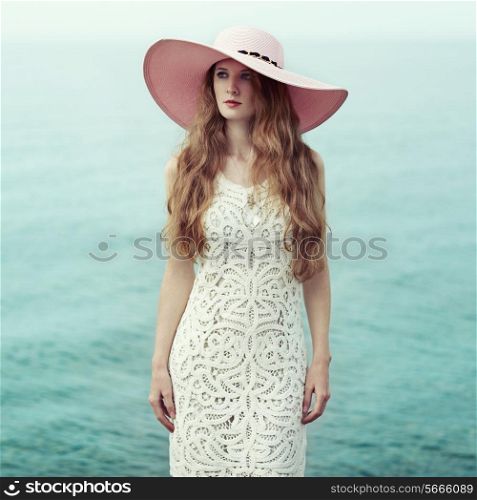 Beautiful woman in hat on the sea. Fashion photo