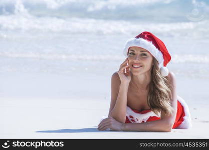 Beautiful woman in Mrs. Claus custume on tropical beach, Christmas vacations concept