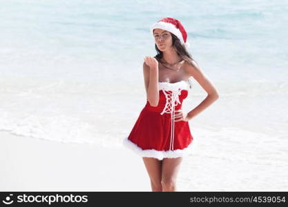 Beautiful woman in Mrs. Claus custume on tropical beach, Christmas vacations concept