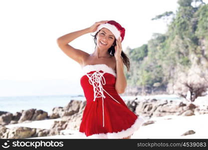 Beautiful woman in Mrs. Claus custume on tropical beach, Christmas vacations concept