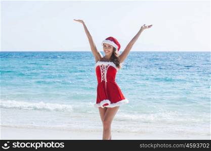 Beautiful woman in Mrs. Claus custume on tropical beach, Christmas vacations concept