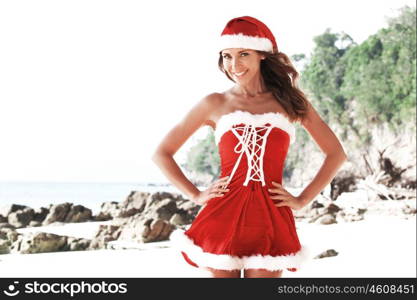 Beautiful woman in Mrs. Claus custume on tropical beach, Christmas vacations concept