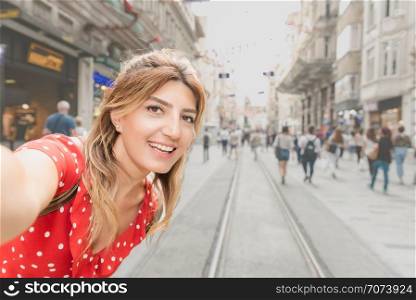 Beautiful woman in red dress takes selfie at Istiklal street,a popular location in Beyoglu district,Istanbul,Turkey. Beautiful woman in red dress takes selfie at Istiklal street