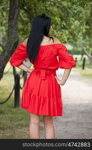 Beautiful woman in red dress walking summer street