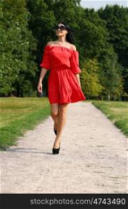 Beautiful woman in red dress walking summer street