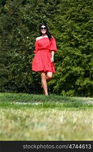 Beautiful woman in red dress walking summer street